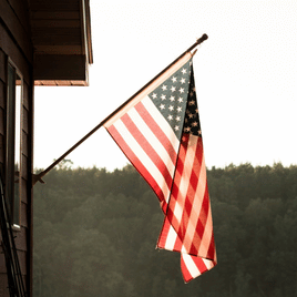 a photo of an american flag hanging off a pole mounted to a house, representing the american flags collection