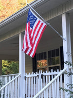 An American flag and pole attached to a front porch.